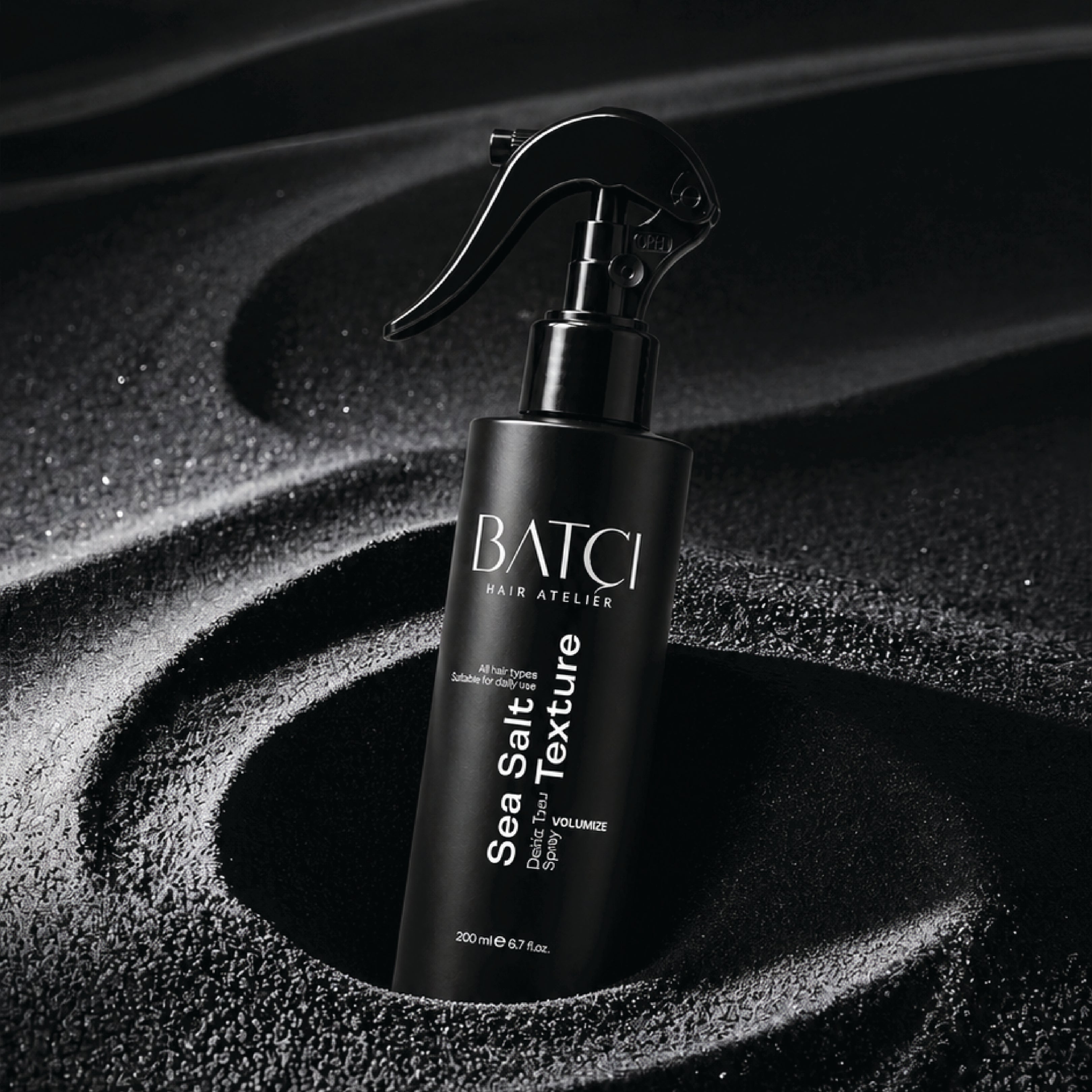 Batci Sea Salt spray placed on a black textured sand.
